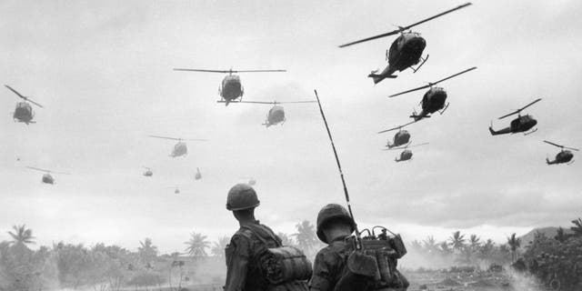 The second wave of combat helicopters of the 1st Air Cavalry Division fly over an RTO and his commander on an isolated landing zone during Operation Pershing during the Vietnam War. (Photo by Patrick Christain/Getty Images)