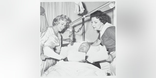 Mel Blanc was critically injured in an automobile accident. During his recovery, he kept busy with his voices. This photo shows him recording the voice of Barney Rubble with Jean Vanderpyl (L) and Bea Benaderet - the voices of Wilma Flintstone and Betty Rubble - on ABC-TV's ‘The Flintstones’.