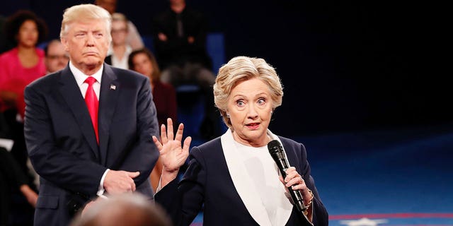 FILE – Democratic presidential nominee former Secretary of State Hillary Clinton ( speaks as Republican presidential nominee Donald Trump listens during the town hall debate at Washington University on October 9, 2016 in St Louis, Missouri. 