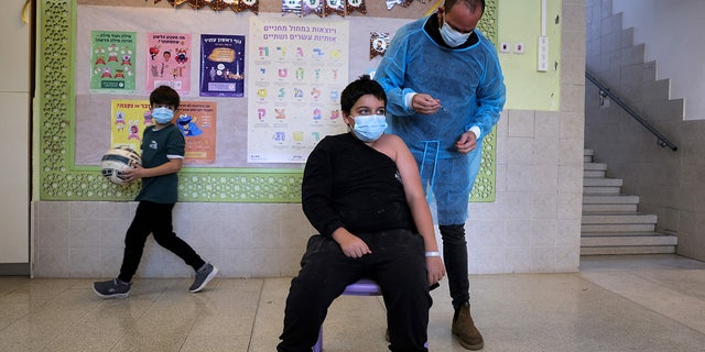 Yinon Weinstock, de 9 años, recibe una dosis para niños de la vacuna contra el coronavirus Pfizer-BioNTech COVID-19 en la escuela primaria Hadasim en la ciudad israelí de Tzur Hadassah, al suroeste de Jerusalén.  (Foto de MENAHEM KAHANA / AFP a través de Getty Images)