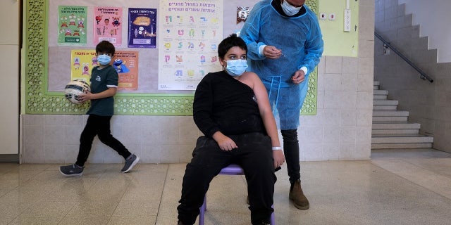 Yinon Weinstock, de 9 años, recibe una dosis para niños de la vacuna contra el coronavirus Pfizer-BioNTech COVID-19 en la escuela primaria Hadasim en la ciudad israelí de Tzur Hadassah, al suroeste de Jerusalén.  (Foto de MENAHEM KAHANA / AFP a través de Getty Images)