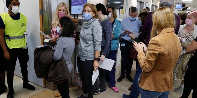 Staff volunteers line up to receive a fourth dose of the Pfizer-BioNTech COVID-19 coronavirus vaccine at the Sheba Medical Center in Ramat Gan near Tel Aviv, on December 27, 2021. (Photo by JACK GUEZ / AFP) (Photo by JACK GUEZ/AFP via Getty Images)