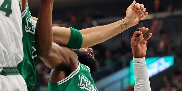 Boston Celtics forward Jayson Tatum, center, chips the tooth of guard Jaylen Brown, right, while reaching for a rebound against Milwaukee Bucks forward Giannis Antetokounmpo (34) during the first half of an NBA basketball game, Saturday, Dec. 25, 2021, in Milwaukee.