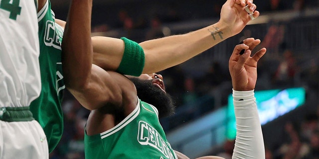 Boston Celtics forward Jayson Tatum, center, chips the tooth of guard Jaylen Brown, right, while reaching for a rebound against Milwaukee Bucks forward Giannis Antetokounmpo (34) during the first half of an NBA basketball game, Saturday, Dec. 25, 2021, in Milwaukee.