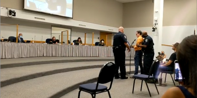 Jeremy Story getting escorted out of a Round Rock ISD school board meeting.
