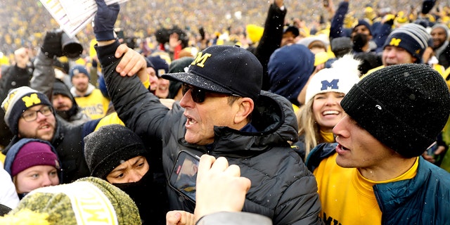 ANN ARBOR, MICHIGAN - NOVEMBER 27: Head Coach Jim Harbaugh of the Michigan Wolverines celebrates with fans after defeating the Ohio State Buckeyes at Michigan Stadium on November 27, 2021 in Ann Arbor, Michigan.