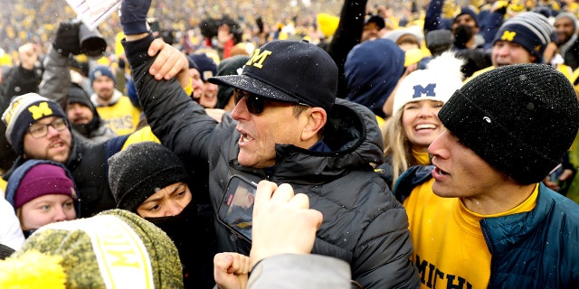 Head Coach Jim Harbaugh of the Michigan Wolverines celebrates with fans after defeating the Ohio State Buckeyes at Michigan Stadium on November 27, 2021 in Ann Arbor, Michigan.