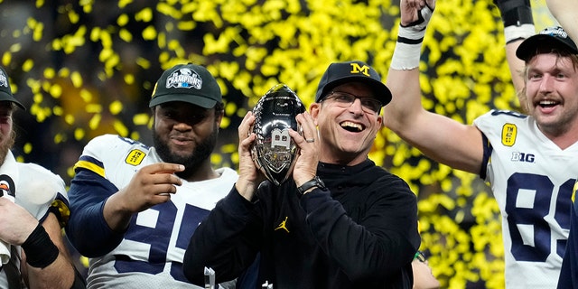 Michigan head coach Jim Harbaugh celebrates with his team after the Big Ten championship game against Iowa, Saterdag, Des. 4, 2021, in Indianapolis. Michigan won 42-3.