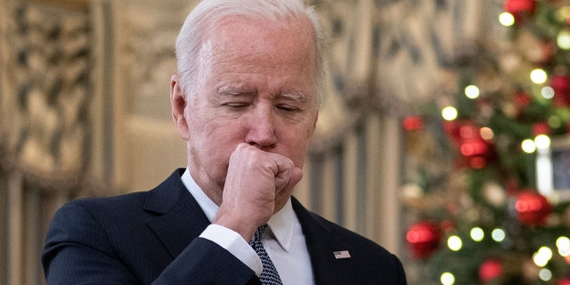 President Biden coughs as he talks to reporters about the November Jobs Report from the State Dining Room of the White House in Washington, D.C., on Dec. 3, 2021.