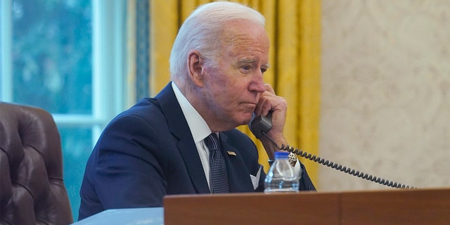In this image made through a window, President Biden talks on the phone with Ukrainian President Volodymyr Zelenskyy from the Oval Office of the White House in Washington, Thursday, Dec. 9, 2021.