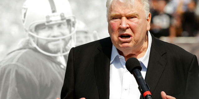 L'ancien entraîneur-chef des Oakland Raiders, John Madden, parle de l'ancien quart-arrière Ken Stabler, photographié à l'arrière, lors d'une cérémonie en l'honneur de Stabler à la mi-temps d'un match de football de la NFL entre les Raiders et les Bengals de Cincinnati à Oakland, Californie, le 13 septembre 2015.