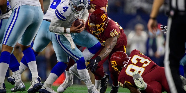 Dallas Cowboys quarterback Dak Prescott (4) is tackled by Washington football defensive tackle Daron Payne (94) and defensive tackle Jonathan Allen (93) during the first quarter at AT&T Stadium.