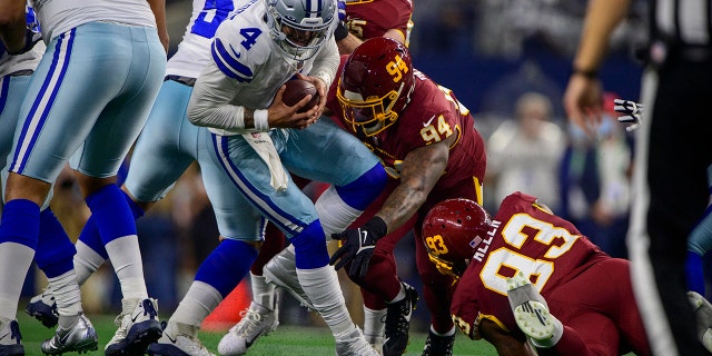 Dec 26, 2021; Arlington, Texas, USA; Dallas Cowboys quarterback Dak Prescott (4) is tackled by Washington Football Team defensive tackle Daron Payne (94) and defensive tackle Jonathan Allen (93) during the first quarter at AT&amp;T Stadium.