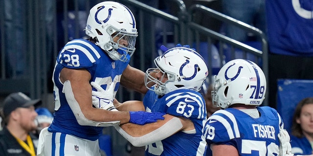 Indianapolis Colts running back Jonathan Taylor (28) is congratulated by Kylen Granson (83) and Eric Fisher (79) after scoring on a 67-yard touchdown run during the second half of an NFL football game against the New England Patriots Saturday, dic. 18, 2021, in Indianapolis.