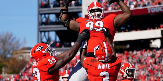 Georgia defensive lineman Jordan Davis (99) is lifted into the air by running back Zamir White (3) and offensive lineman Justin Shaffer (54) after scoring a touchdown in the first half of an NCAA college football game against Charleston Southern, 星期六, 十一月. 20, 2021, in Athens, 嘎.