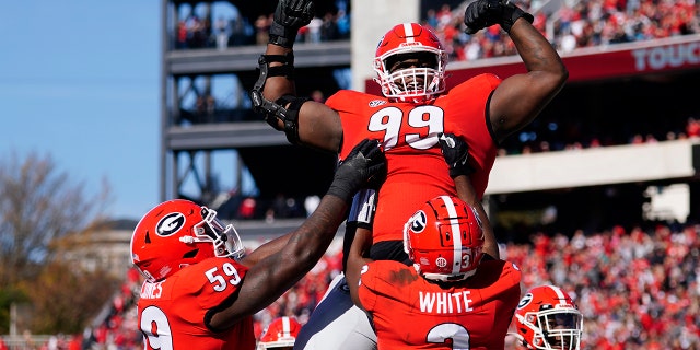 Georgia defensive lineman Jordan Davis (99) is lifted into the air by running back Zamir White (3) and offensive lineman Justin Shaffer (54) after scoring a touchdown in the first half of an NCAA college football game against Charleston Southern, Saturday, Nov. 20, 2021, in Athens, Ga.