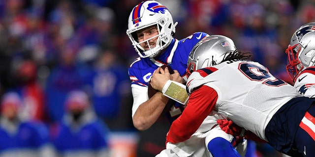O quarterback do Buffalo Bills, Josh Allen (17), é enfrentado pelo New England Patriots fora do linebacker Matt Godon (9) durante a primeira metade de um jogo de futebol americano da NFL em Orchard Park, Nova York, segunda-feira, 6 de dezembro de 2021.