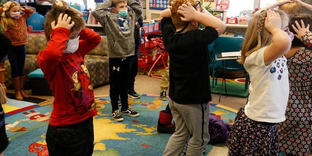 Second-graders hold their heads as they talk about "thoughts" and how they compare with "feelings" and resulting "actions," at Paw Paw Elementary School on Thursday, Dec. 2, 2021. 