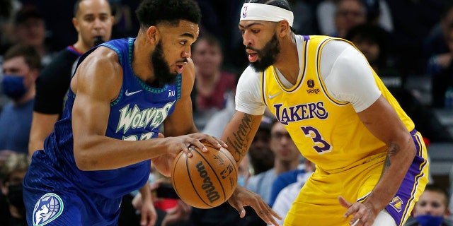 Minnesota Timberwolves center Karl-Anthony Towns (32) works past Los Angeles Lakers forward Anthony Davis (3) in the first quarter of an NBA basketball game Friday, Dec. 17, 2021, in Minneapolis.