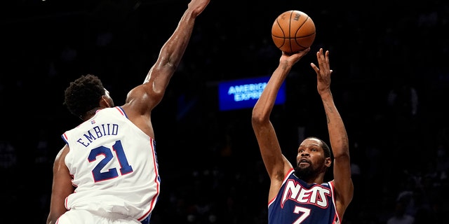 Brooklyn Nets forward Kevin Durant (7) shoots a basket over Philadelphia 76ers center Joel Embiid (21) during the second half of an NBA basketball game, Donderdag, Des. 16, 2021, In New York. The Nets won 114-105.