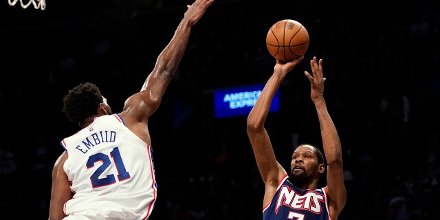 Brooklyn Nets forward Kevin Durant (7) shoots a basket over Philadelphia 76ers center Joel Embiid (21) during the second half of an NBA basketball game, Donderdag, Des. 16, 2021, In New York. The Nets won 114-105.