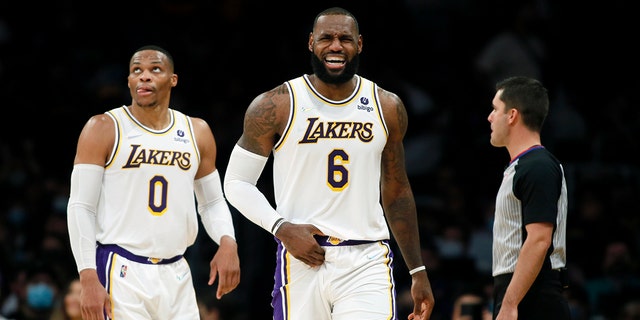 Los Angeles Lakers forward LeBron James, center, grimaces after making a basket against the Detroit Pistons, with guard Russell Westbrook, left, looking up at a video replay during the second half of an NBA basketball game Sunday, Nov. 28, 2021, in Los Angeles.