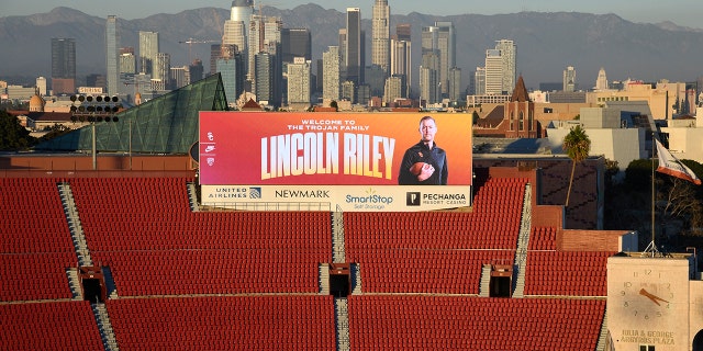 A large screen at the Los Angeles Coliseum display a photo of the new USC football head coach Lincoln Riley, with downtown Los Angeles in the background on Nov. 29, 2021.