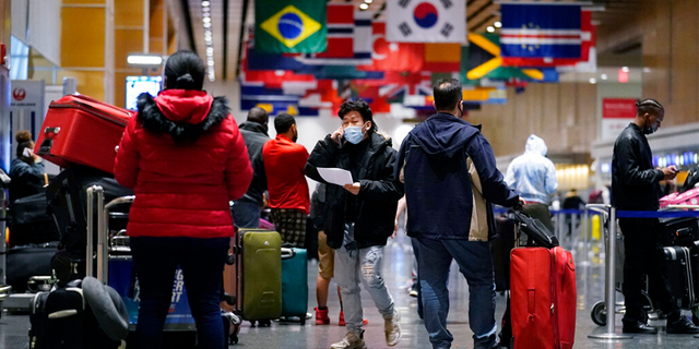 Travelers wait in line to check in for flights at Logan Airport, Tuesday, Dec. 21, 2021, in Boston.