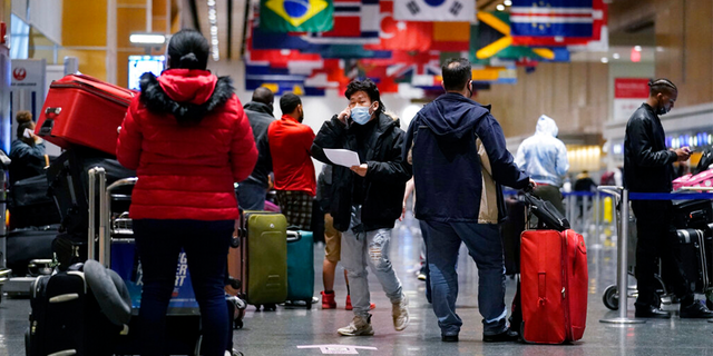 Travelers wait in line to check in for flights at Logan Airport, Tuesday, Dec. 21, 2021, in Boston.