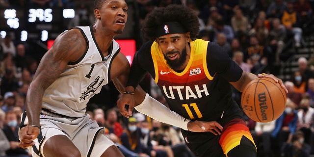 Utah Jazz guard Mike Conley (11) drives the basket as San Antonio Spurs guard Lonnie Walker IV (1) defends during the second half of an NBA basketball game on Friday, Dic. 17 2021, a Salt Lake City.