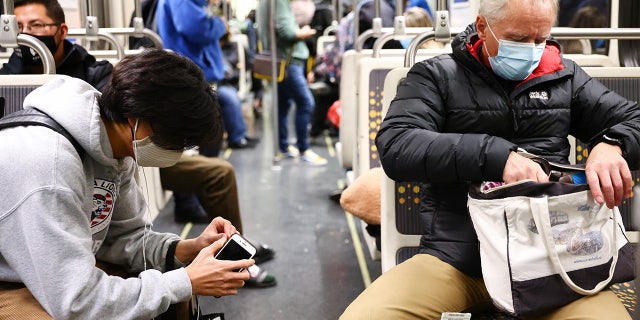 People wear face coverings while riding a Los Angeles Metro Rail train on December 15, 2021 in Los Angeles, California. (Photo by Mario Tama/Getty Images)