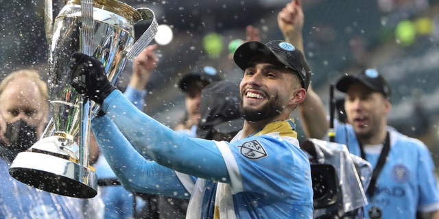 New York City FC forward Valentin Castellanos (11) celebrates with the trophy after their penalty kick shootout win over the Portland Timbers in the MLS Cup soccer game, Saturday, Dec. 11, 2021, in Portland, Ore. (AP Photo/Amanda Loman)