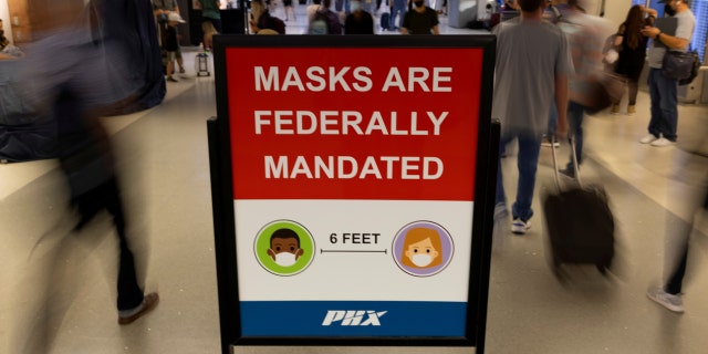 Air travelers pass a sign mandating face masks at Phoenix international airport in Arizona on Sept. 24, 2021.