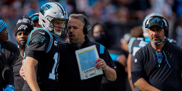 Carolina Panthers head coach Matt Rhule talks with quarterback Sam Darnold during the first half of an NFL football game against the Tampa Bay Buccaneers Sunday, Dec. 26, 2021, in Charlotte, N.C.