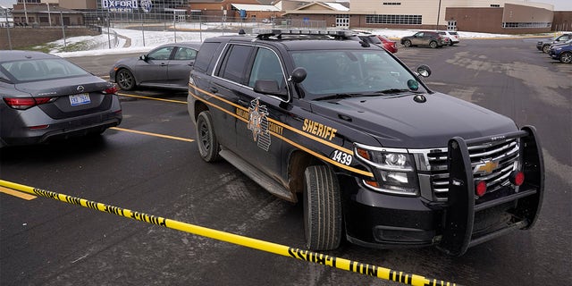 An Oakland County Sheriff's deputy guards the parking lot of Oxford High School in Oxford, Mich., Wednesday, Dec. 1, 2021. A 15-year-old sophomore opened fire at the school, killing several students and wounding multiple other people, including a teacher. (AP Photo/Paul Sancya)