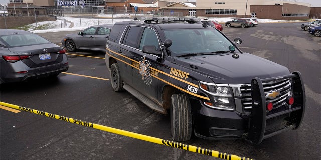 An Oakland County Sheriff's deputy guards the parking lot of Oxford High School in Oxford, Mich., Wednesday, Dec. 1, 2021. A 15-year-old sophomore opened fire at the school, killing several students and wounding multiple other people, including a teacher. (AP Photo/Paul Sancya)