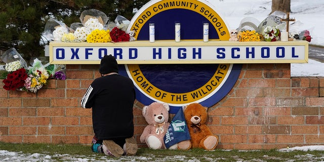 A well-wisher kneels to pray at a memorial on the sign of Oxford High School in Oxford, Mich., on Wednesday.