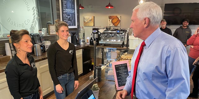 Former Vice President Mike Pence speaks with the owners of Simply Delicious Baking Co., on Dec. 8, 2021, in Bedford, New Hampshire.