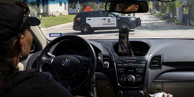 A local resident looks at a police vehicle driving along a street in north of Minneapolis, Minnesota, U.S. September 9, 2021.