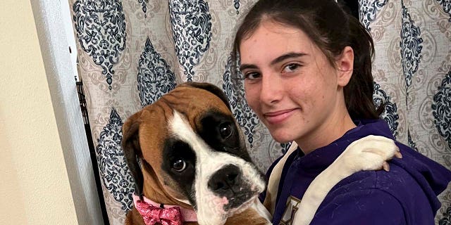 This provided by Cheri Burness shows Miranda Burness and the family dog Lilikoi in Honolulu on Thursday, Dec. 2, 2021.