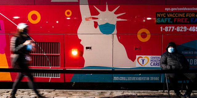 Um local móvel de vacinação e dose de reforço COVID-19 opera em um ônibus na 59th Street ao sul do Central Park enquanto os pacientes esperam na calçada, quinta-feira, 2 de dezembro de 2021, em Nova York.