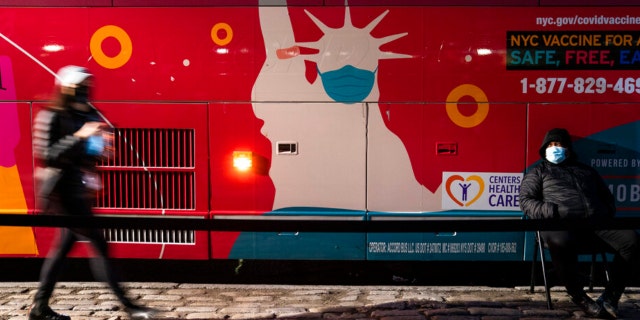 Um local móvel de vacinação e dose de reforço COVID-19 opera em um ônibus na 59th Street ao sul do Central Park enquanto os pacientes esperam na calçada, quinta-feira, 2 de dezembro de 2021, em Nova York.