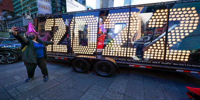 Teresa Hui poses for a selfie in front of a 2022 sign displayed in Times Square, New York.