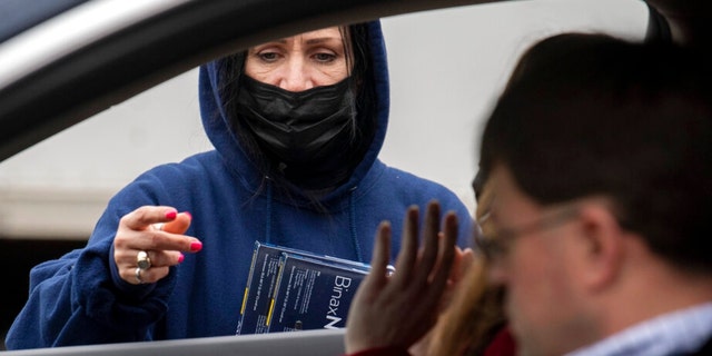 Youngstown City Heath Department worker Kathy Johnson talks with drivers before giving them at-home COVID-19 test kits during a distribution event, Thursday, Dec. 30, 2021, in Youngstown, Ohio. (AP Photo/David Dermer)