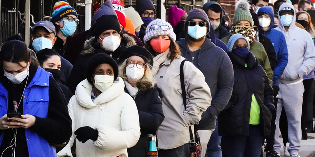 People wait in a line extending around the block to receive free at-home rapid COVID-19 test kits in Philadelphia on Monday, December 21, 2021.