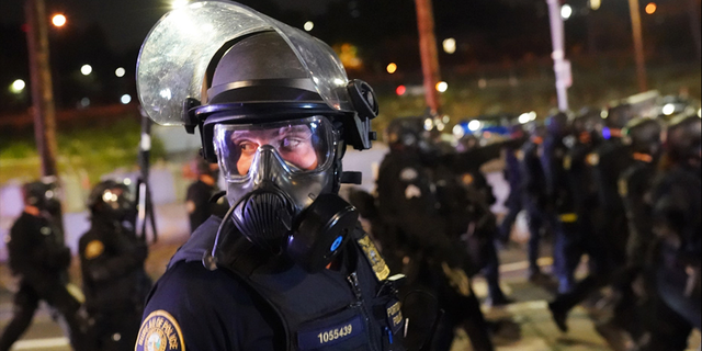 ​​​​​​​A Portland, Oregon, police officer scans the crowd while dispersing protesters, Aug. 21, 2020. 