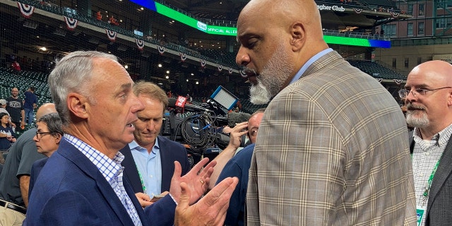 Baseball Commissioner Rob Manfred, left, and Major League Baseball Players Association executive director Tony Clark speak before Game 1 in baseball's World Series between the Houston Astros and the Atlanta Braves, Oct. 26, 2021, in Houston.