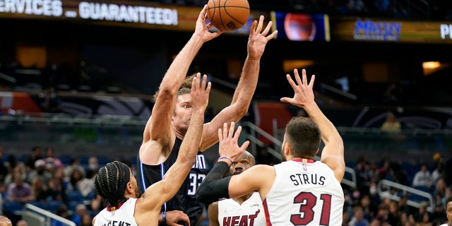 Orlando Magic center Robin Lopez, 센터, passes the ball as he is trapped by Miami Heat guard Gabe Vincent (2), center Dewayne Dedmon (21) and guard Max Strus (31) during the second half of an NBA basketball game, 금요일, 12 월. 17, 2021, 올랜도, Fla.