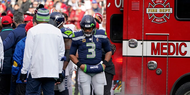 Seattle Seahawks quarterback Russell Wilson (3) stands near an ambulance before it took San Francisco 49ers running back Trenton Cannon off the field after an injury during the first half of an NFL football game at Lumen Field, 星期日, 十二月. 5, 2021, 在西雅图.