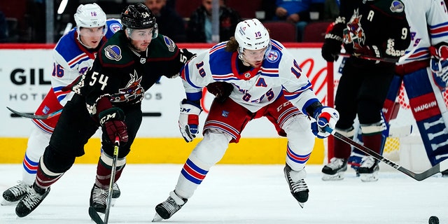 New York Rangers left wing Artemi Panarin (10) keeps the puck away from Arizona Coyotes defenseman Cam Dineen (54) as Rangers center Ryan Strome (16) looks on during the second period of an NHL hockey game Wednesday, Dec. 15, 2021, in Glendale, Ariz. The Rangers won 3-2. 